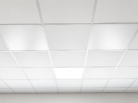Eine Raster-Einlegedecke eines Büroraumes in weiß mit der Panelwave, als Deckenheizelement, die Infrarotwärme ausstrahlt.